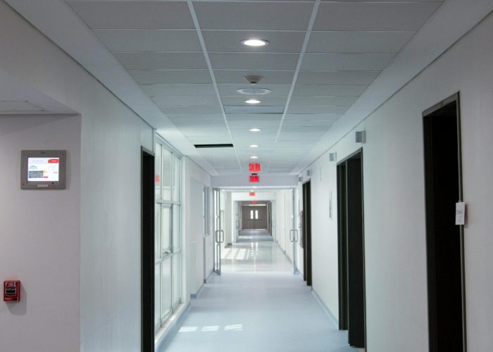 Empty hospital corridor with 'Salida' exit sign, featuring clean design and bright lighting.